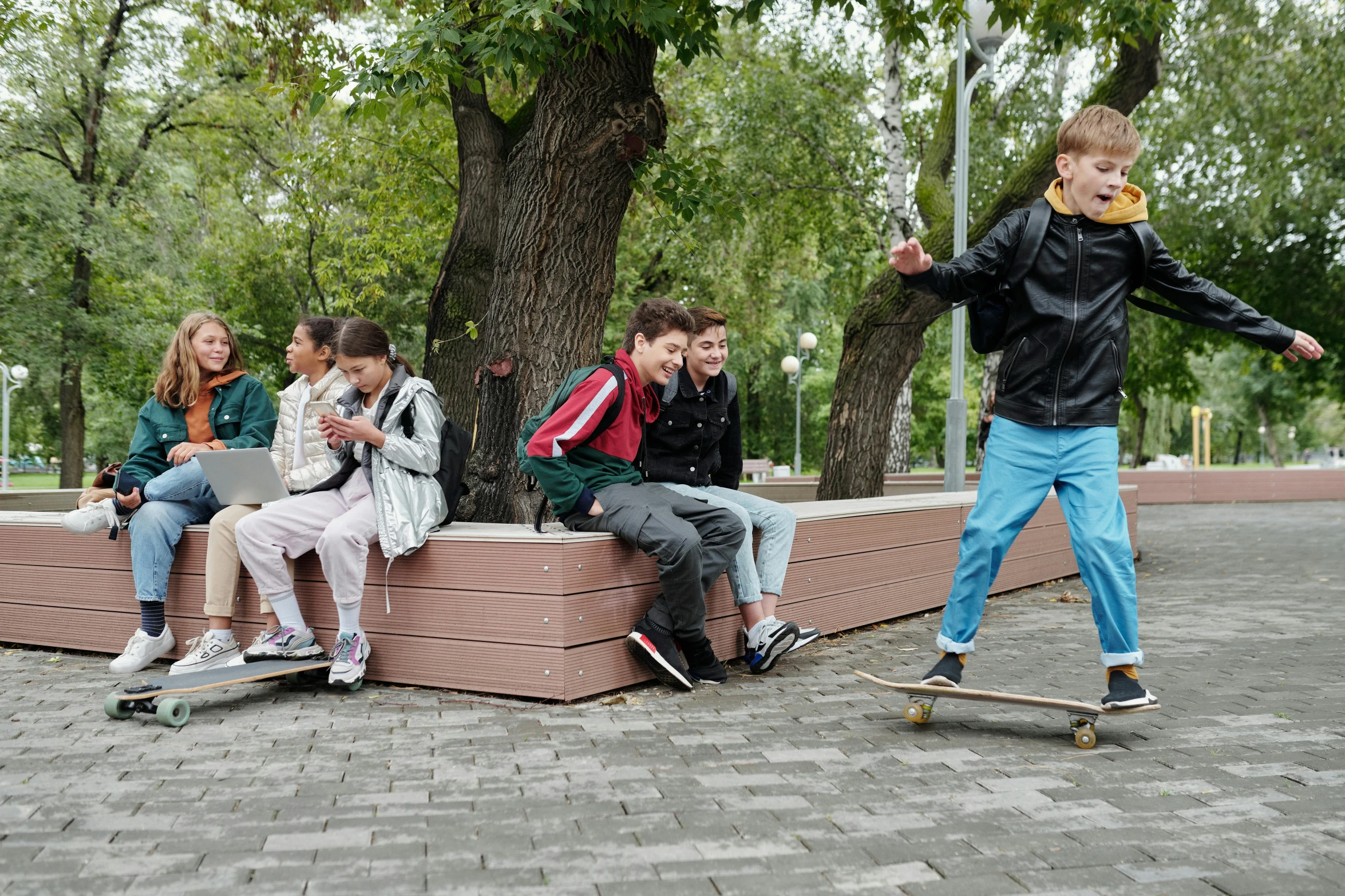 a bunch of people sit on a brick wall with skate boards