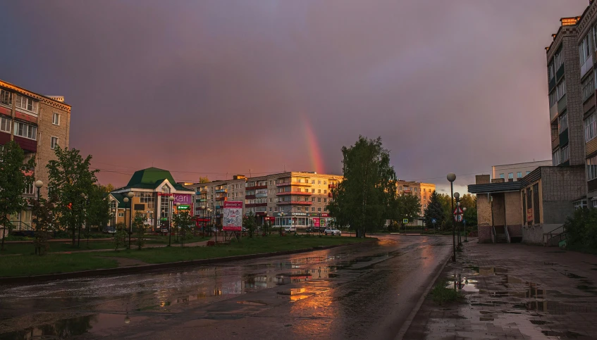 a rain soaked dle in the middle of a city with a rainbow