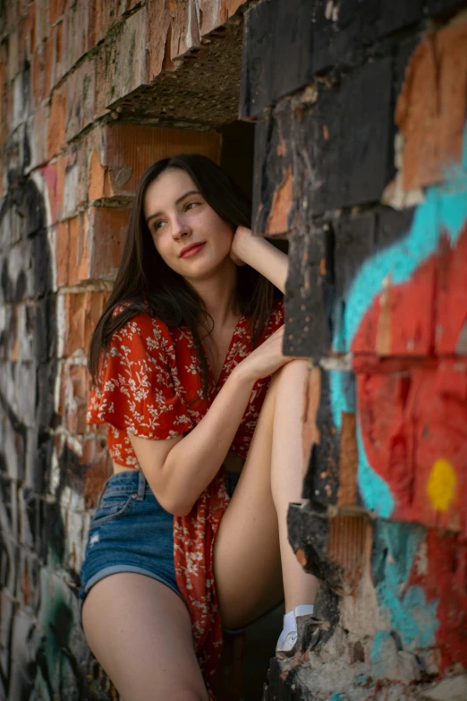 a pretty young lady leaning against a brick wall