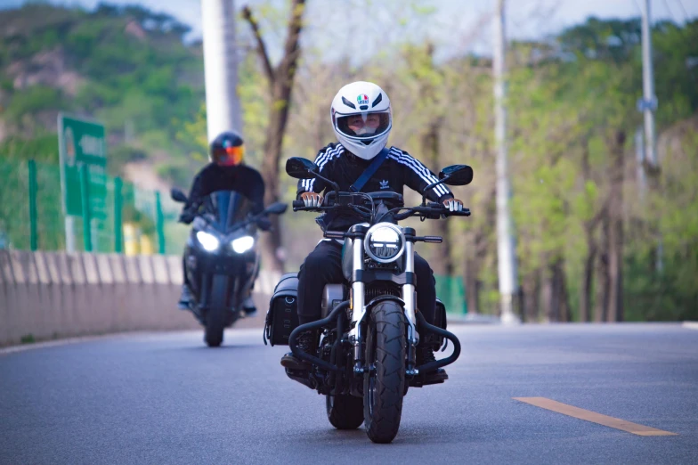 the two people are riding down the street on their motor bikes