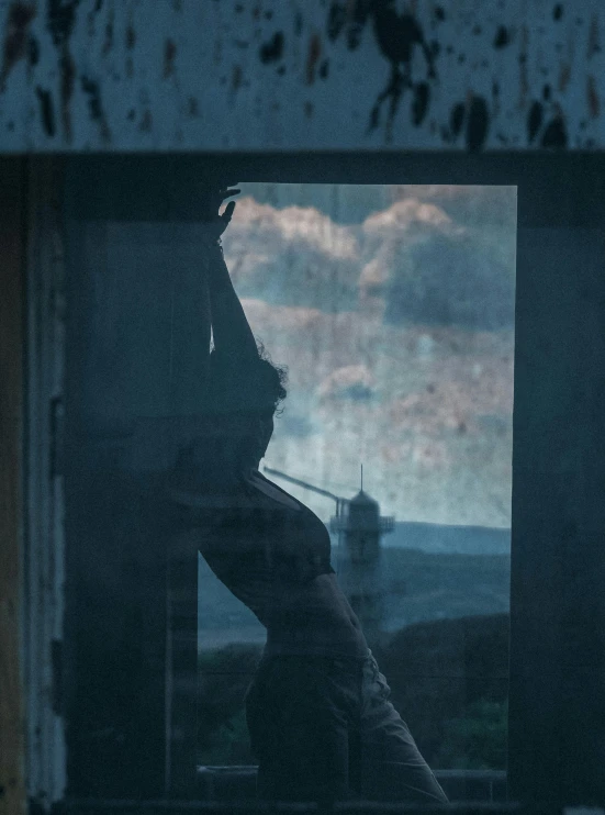 a person in shadow is shown through an old window