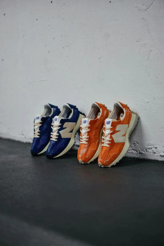 three different colors shoes, two are lined up against a white wall