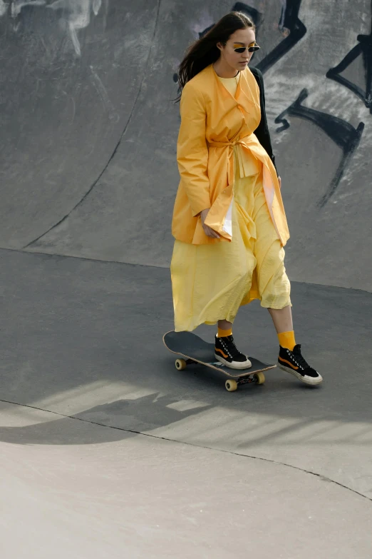 a skateboarder riding through the skate park in her yellow dress