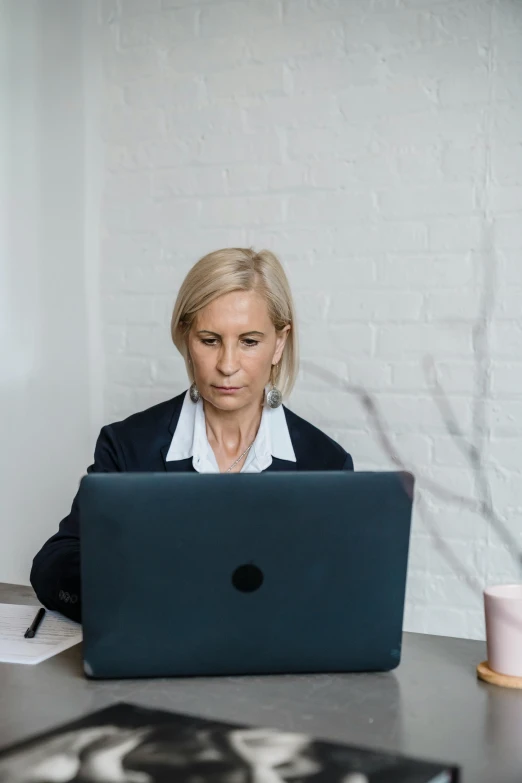 a woman sits at a table with her laptop