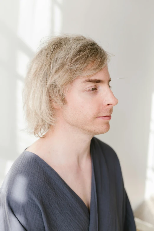 a man standing up in a room with long hair