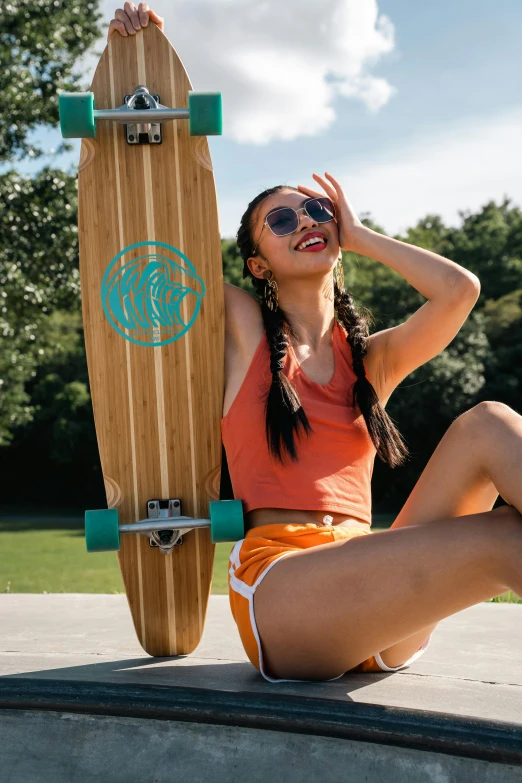 a beautiful woman sitting on the ground next to a skateboard