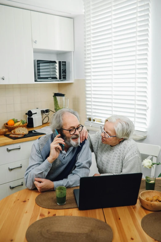 an older couple looks at their laptop in a kitchen