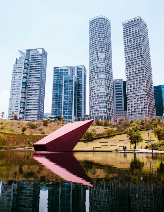 the sculpture in front of the water with skyscrs in the background