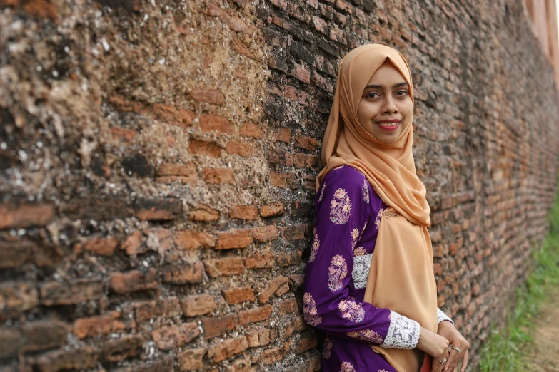 a young woman posing against a brick wall