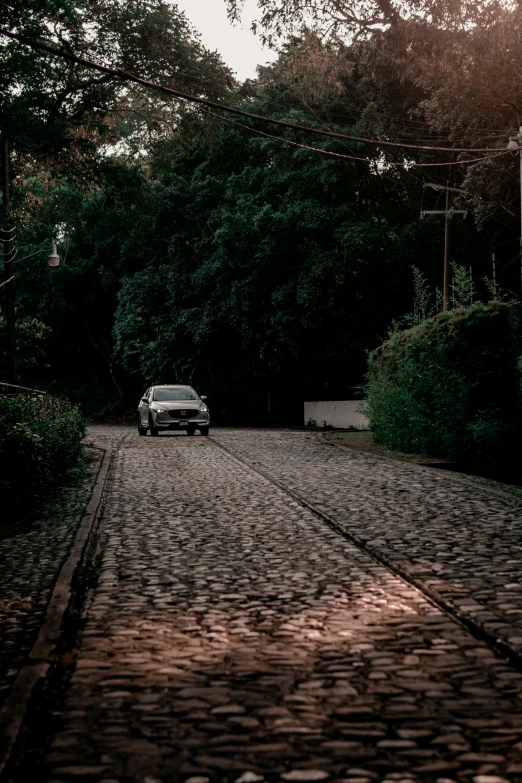 the car is parked on the cobblestone road