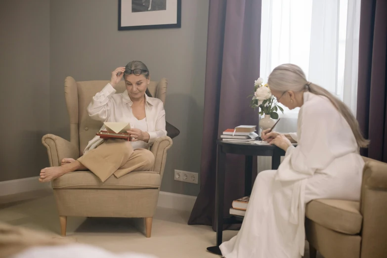 a woman sitting in a chair next to another person