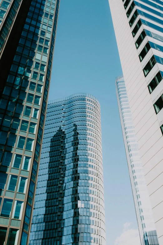 the tall buildings have glass windows against the blue sky