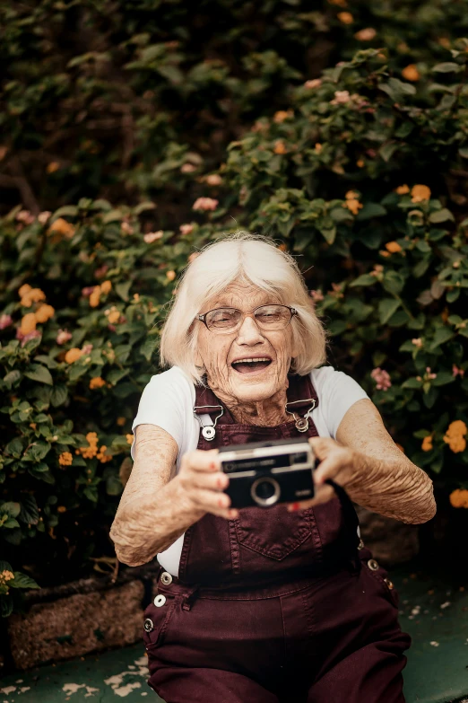 an old lady is holding an old camera in her hands