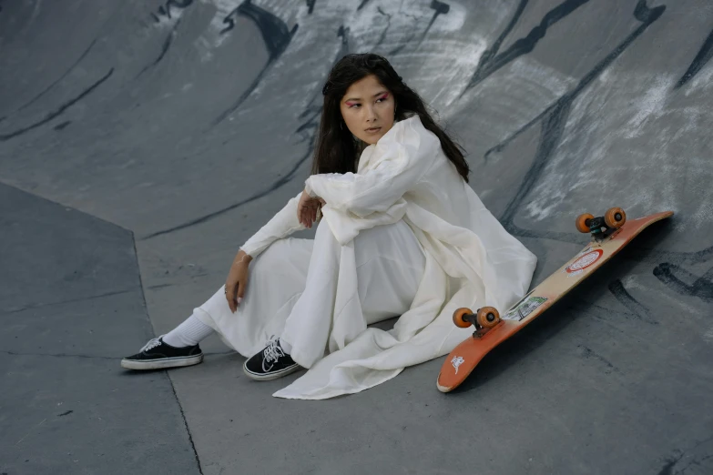 a girl sitting on a skateboard at a skate park