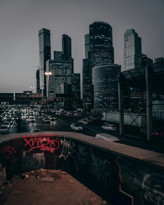 a graffiti - covered ramp overlooking a cityscape in the night