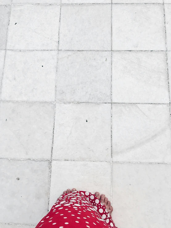 a person in red is walking on a tiled floor