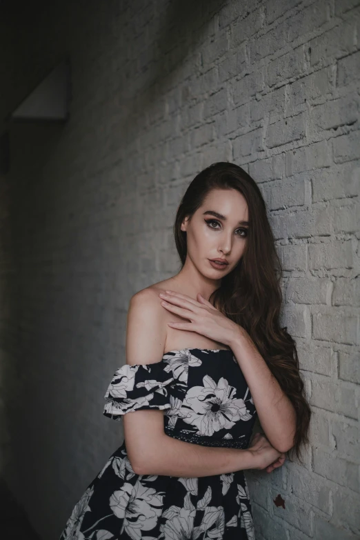 a beautiful woman standing in front of a brick wall