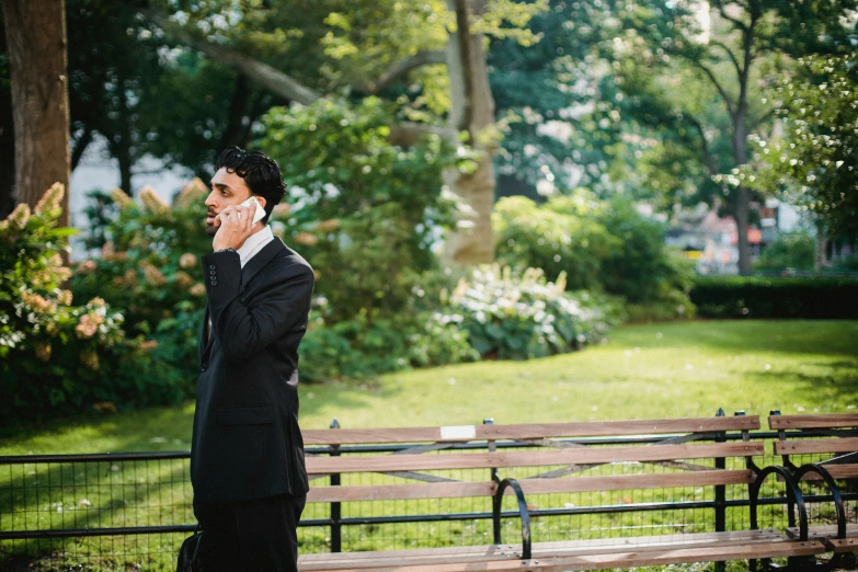 a young man dressed in a suit talking on the phone