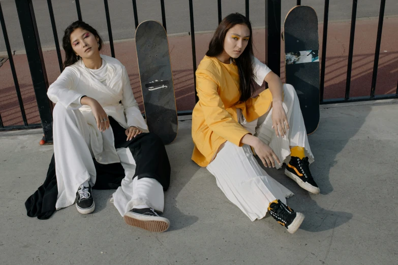 two girls sitting down while one girl is leaning against the gate