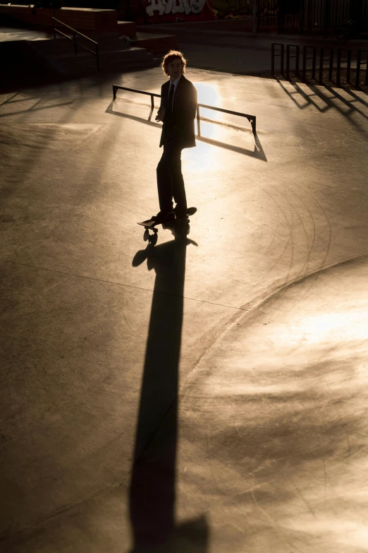 a skateboarder in a dark coat rides on a path