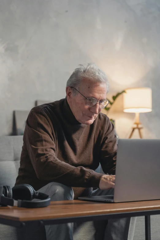 the old man is typing on his laptop