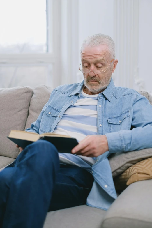 a man that is sitting on a couch reading