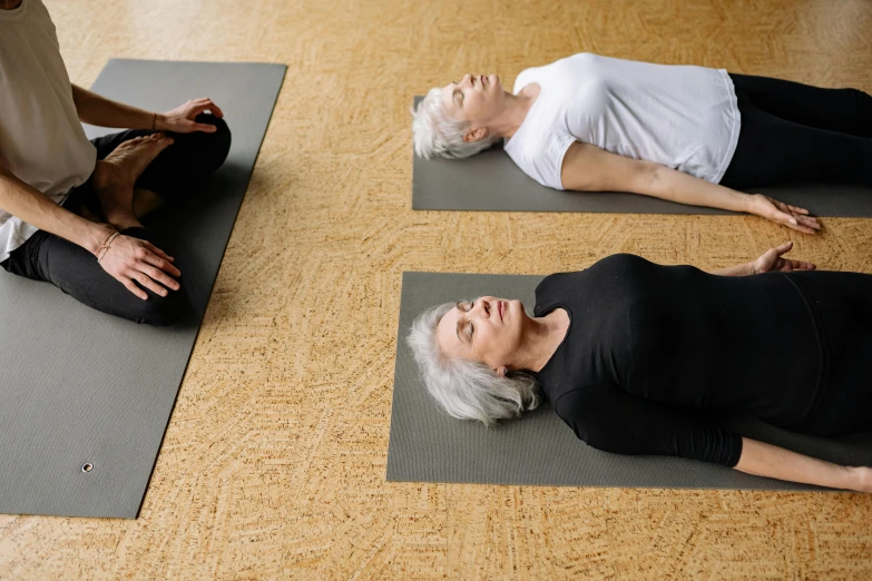 two people laying on yoga mats while each sit in their own directions