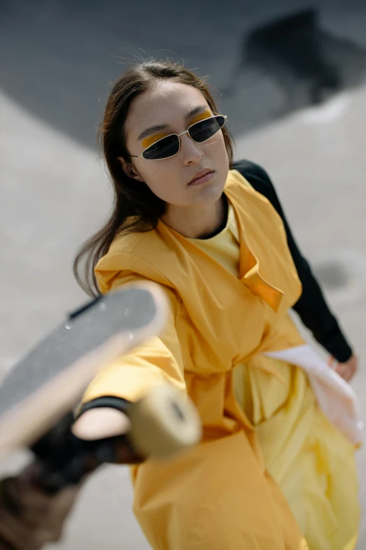 a young woman wearing shades and holding a skateboard