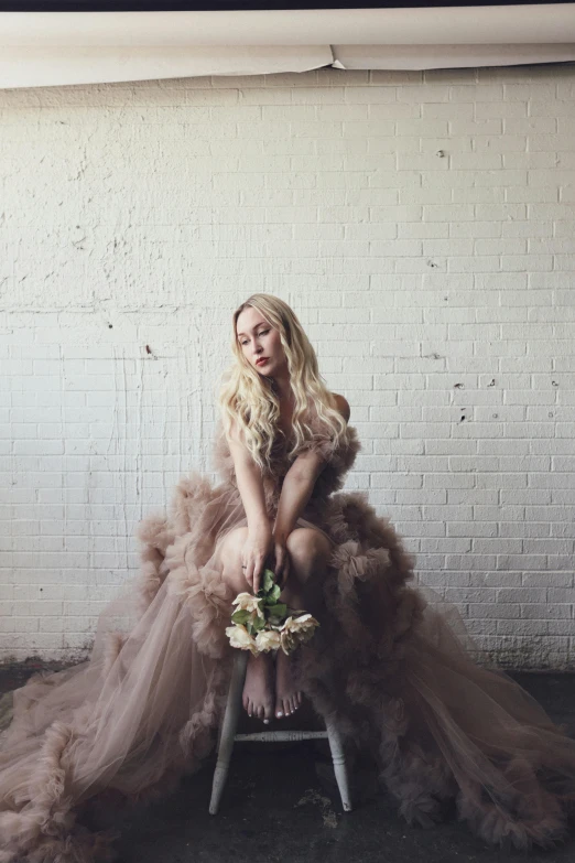 a woman sitting on a chair in a dress and posing