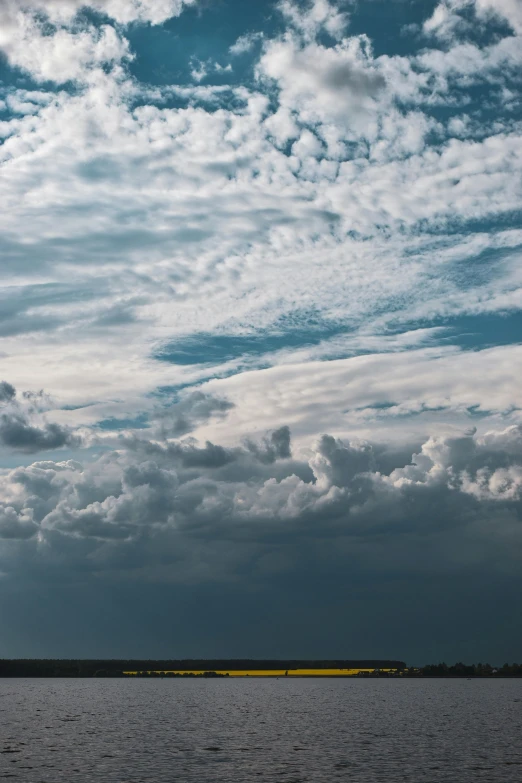 a boat travels across the water as dark clouds hover over the shoreline