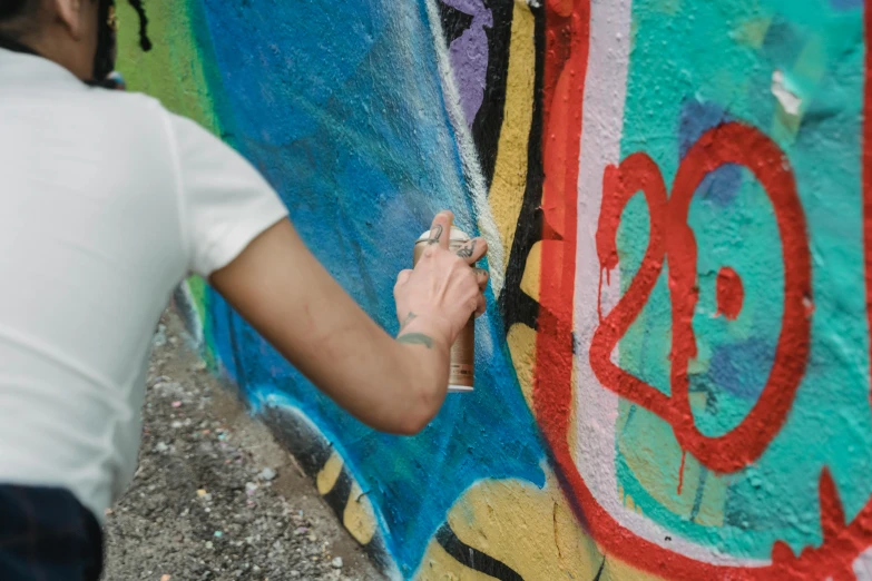 man working on a graffiti wall with white paint