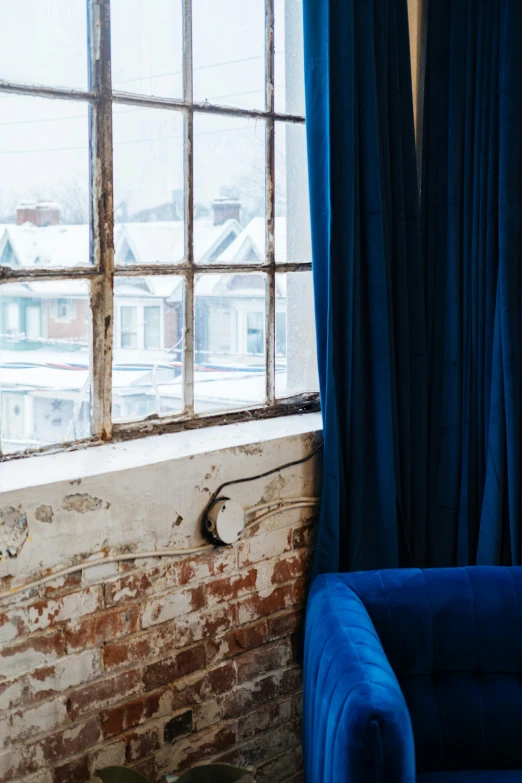 blue velvet chair and large brick wall with old windows