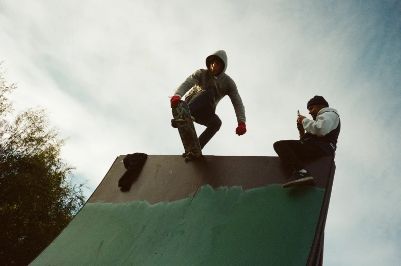 two people skateboarding on the top of a large metal roof