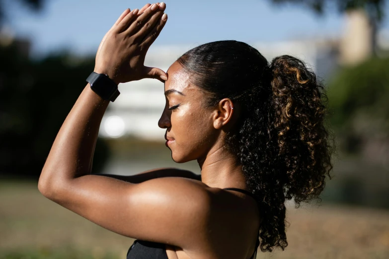 a woman with dark skin holding her hands to her face