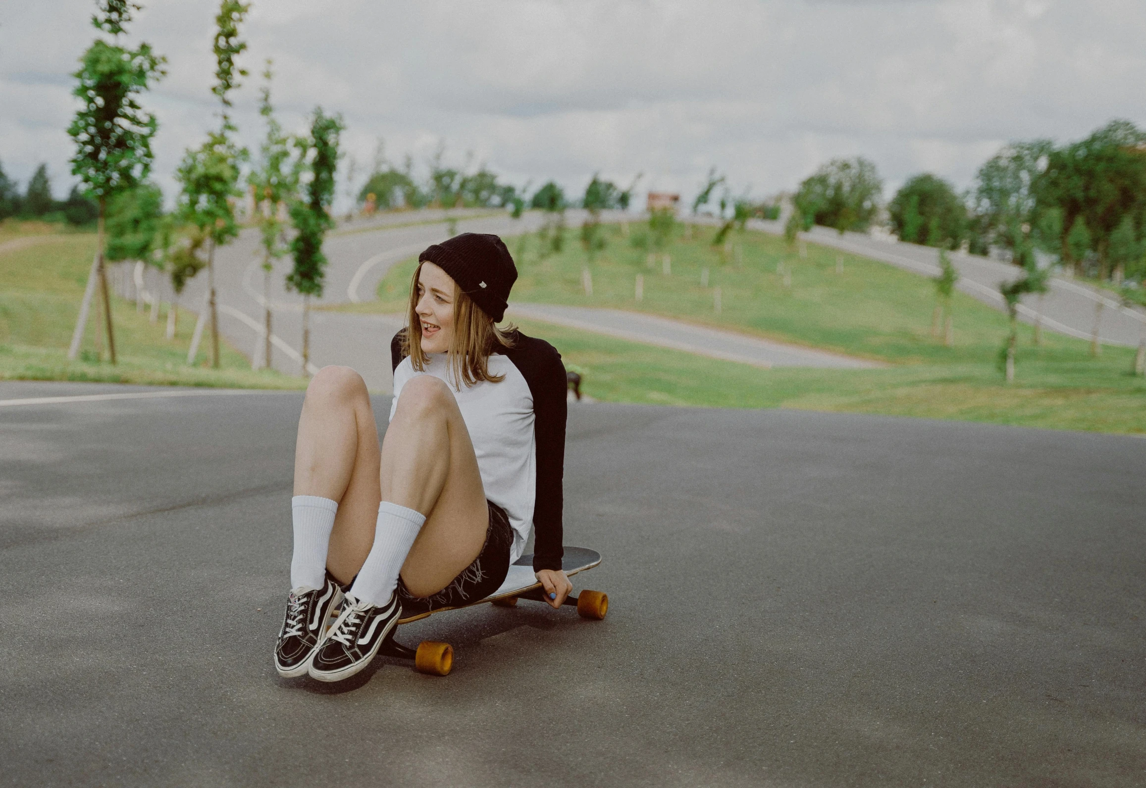 a girl is sitting on her skateboard on the pavement