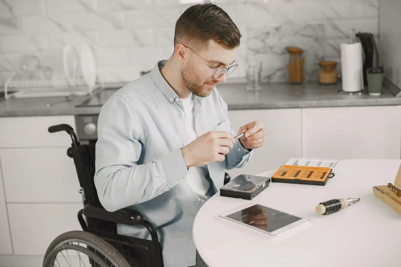 man sitting at a table in a wheelchair next to cell phone