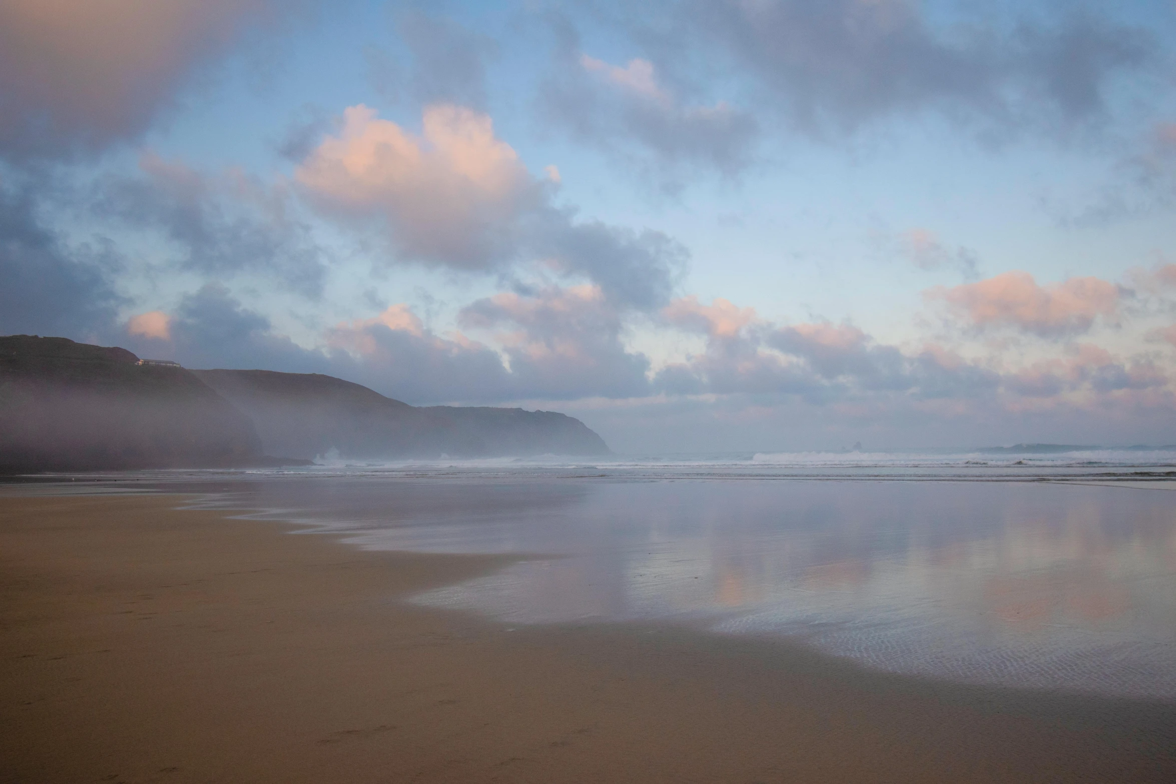 a lone person standing on a beach in front of the ocean