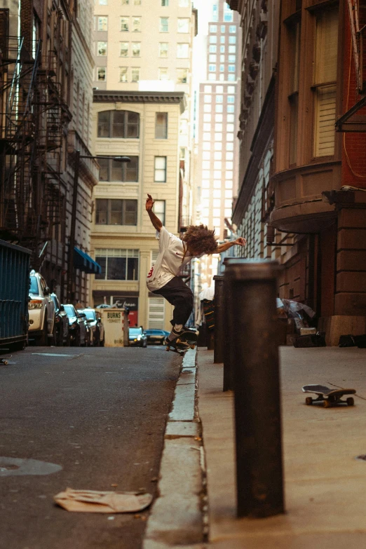 a boy doing a trick on his skateboard while on the sidewalk in a city