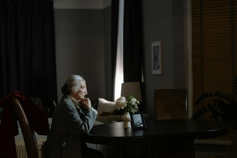 an older woman sitting at a table looking out the window