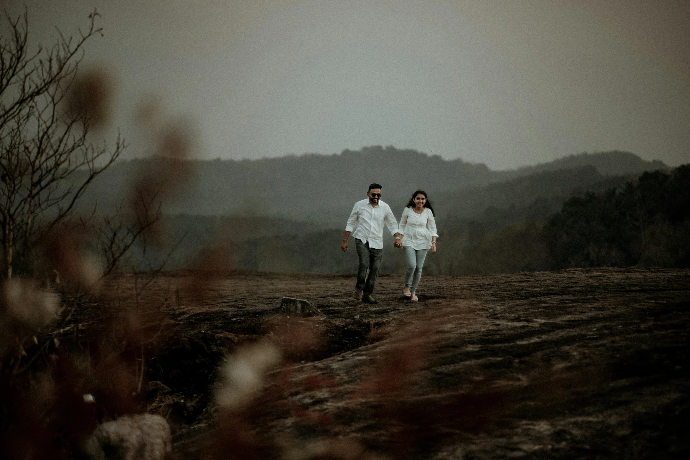 a young couple in the middle of nowhere with mountains behind them