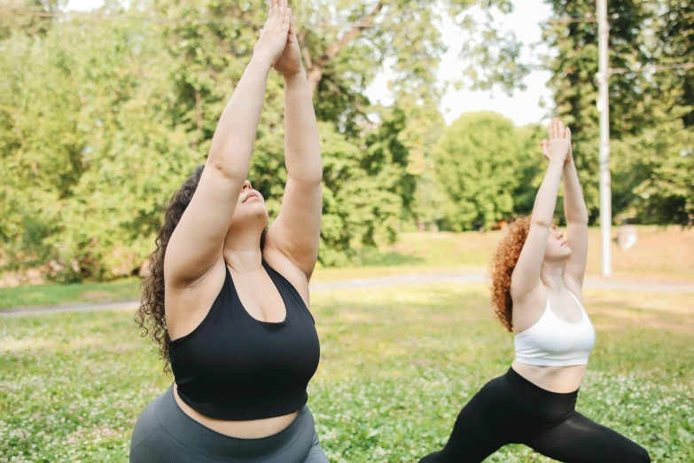 two women practicing yoga in the park on a sunny day