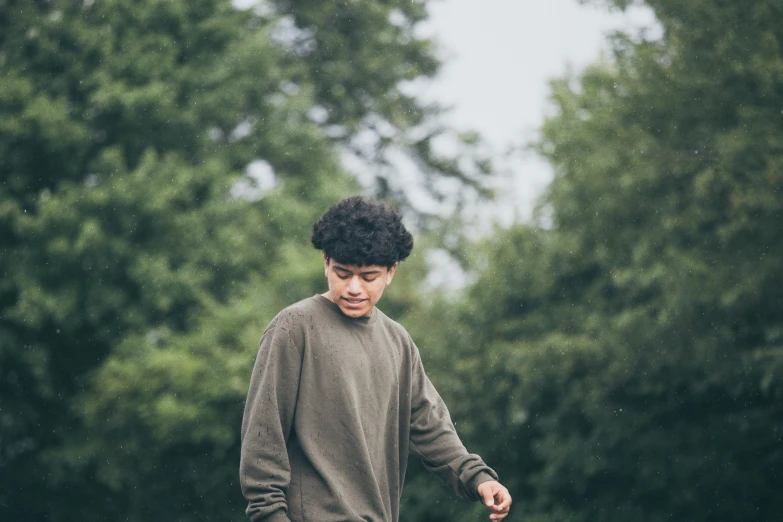 the young man stands on a skateboard in the rain