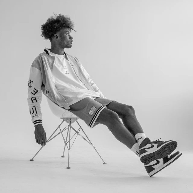 black and white po of man on adidas shoes, sitting in a chair