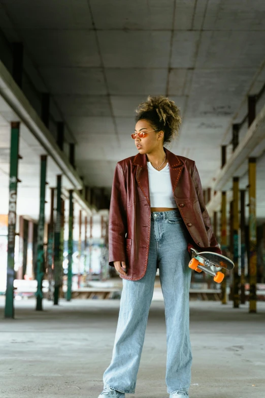 a girl holding a skateboard stands in a parking lot