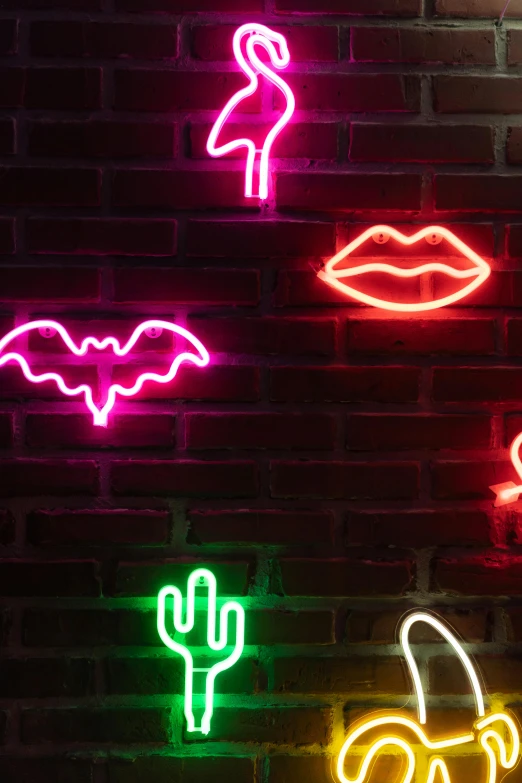 several neon signs are placed near a brick wall