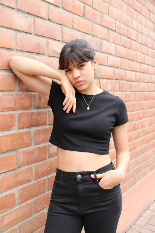 a woman is leaning against a brick wall