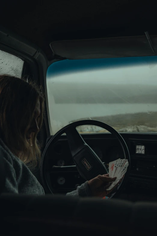 a woman is holding cards while driving a car