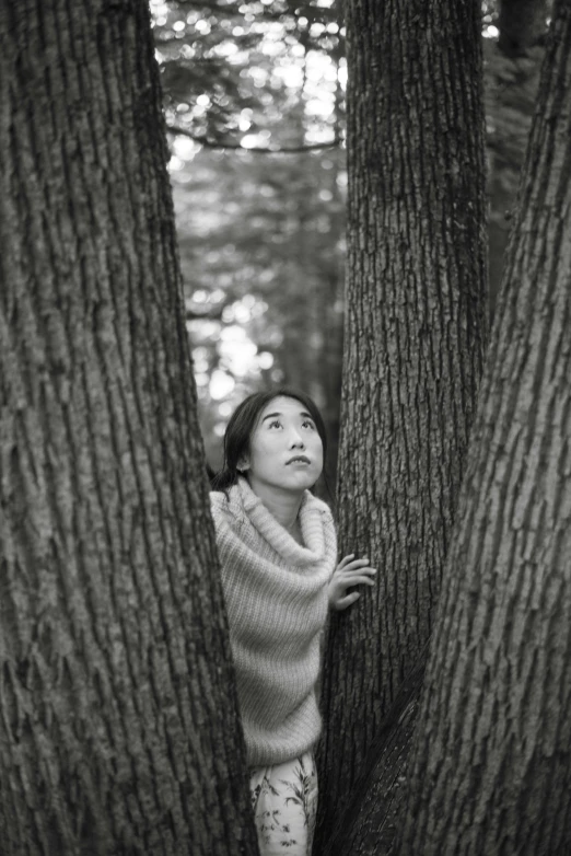 a woman hiding behind two trees