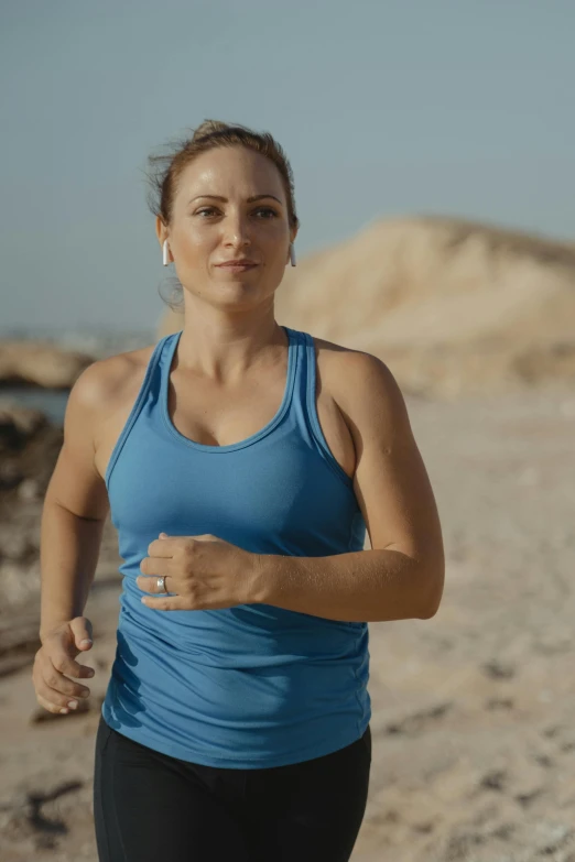 a woman in blue shirt standing by the ocean