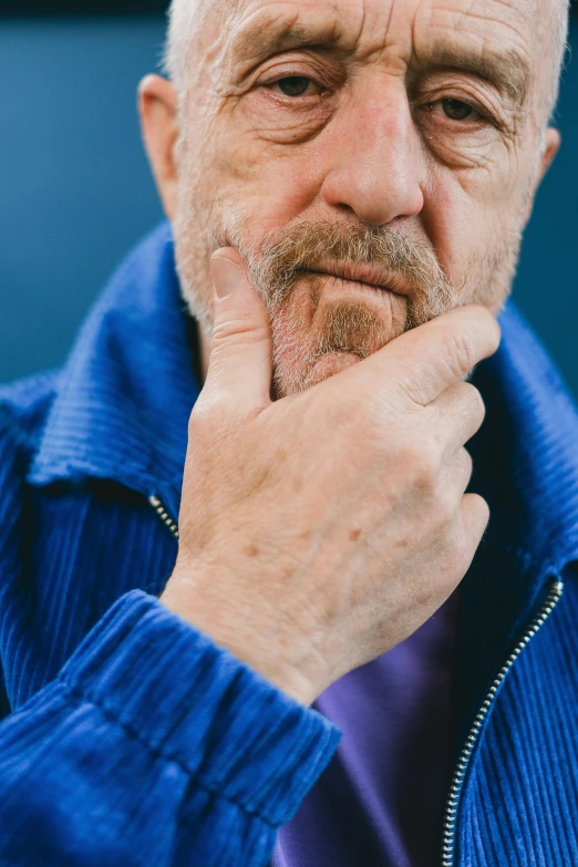 an older man with white hair has his hand on his chin